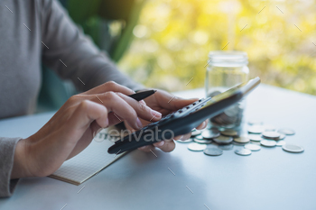 ガラスの瓶にお金を節約し、財務概念を計算してメモする女性 / Photodune, Misc