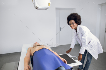 Smiling professional African American woman doctor in uniform posing to camera, while taking chest / Photodune, Misc