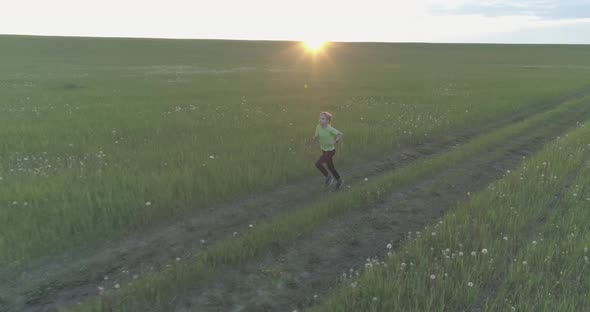 Sporty Child Runs Through a Green Wheat Field. Evening Sport Training Exercises at Rural Meadow. A