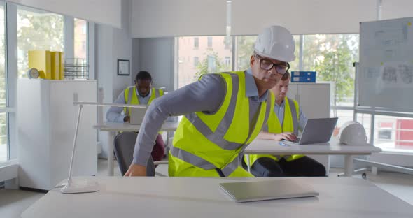 Civil Construction Engineer Working on Laptop at Desk in Office