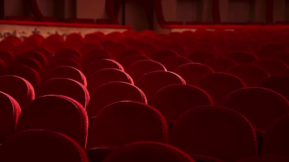 Selective focus on empty rows with red velvet seats in theater hall. Rows with empty chairs. 