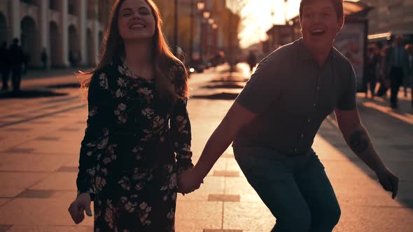 Attractive Handsome Young Couple Is Jumping Down the Street and Laughing.