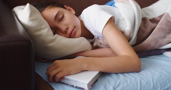 A Girl is Sleeping with a Book Under Her Pillow