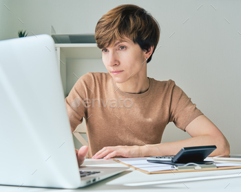 ノートパソコンを見て計算している白人女性。経費を数え、財務記録を保持する / Photodune, Misc