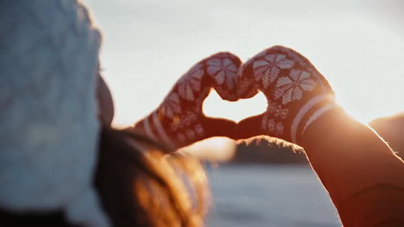 Woman Making Love Heart From Fingers at Morning Winter Sunrise