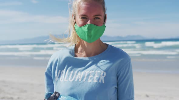 Portrait of caucasian woman wearing volunteer t shirt and face mask looking at camera