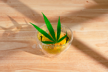 木製のテーブルに熱いマリファナティーのグラス。緑の葉と大麻ハーブティー。 / Photodune, Misc