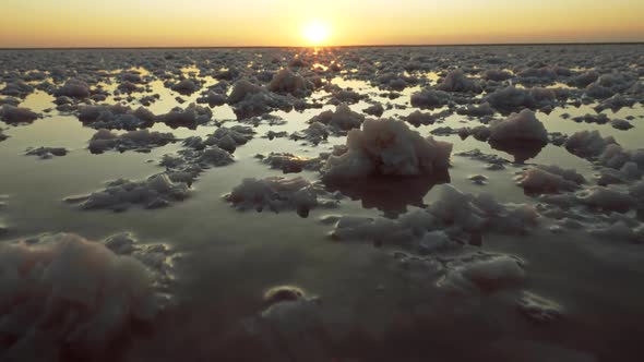 Salt Piles in a Salt Lake During Sunset. Setting Sun in the Background