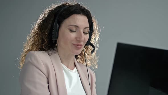 Customer Support Agent or Call Center with Headset Works on Desktop Computer While Supporting the