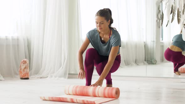 Woman Rolling Up Mat at Yoga Studio or Gym 21