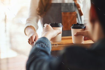 カフェで顧客にホットコーヒーの紙コップを保持し、提供するウェイトレス / Photodune, Misc