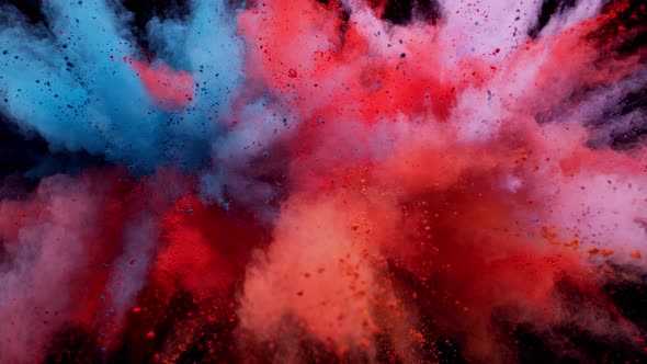 Colorful powder/particles fly after being exploded against black background. Slow Motion. alt
