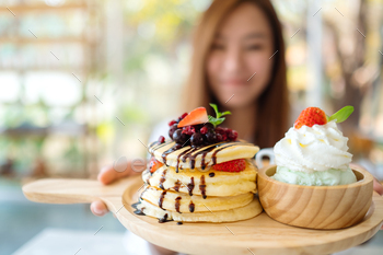 カフェでアイスクリームとホイップクリームとパンケーキのプレートを保持し、見せている女性 / Photodune, Misc
