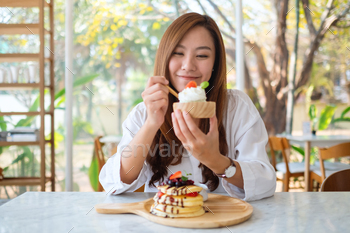 woman eating ice cream with a mixed berries pancakes and whipped cream by wooden spoon / Photodune, Misc