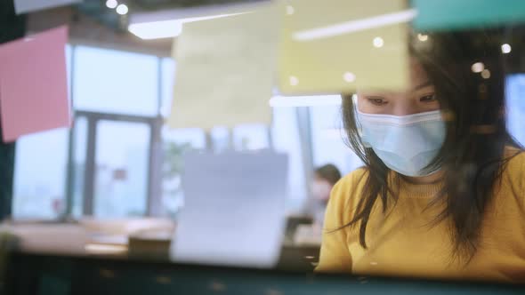 attractive freelance asian female creative person wear casual yellow cloth and face mask