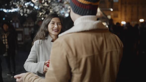 Man Standing Back to Camera Presents a Xmas Gift to Her Girlfriend but She Doesn't Like It