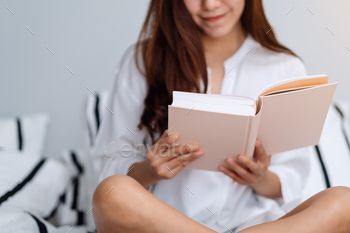 自宅で白い居心地の良いベッドで本を読んでいる美しい女性のクローズアップ画像 / Photodune, Misc