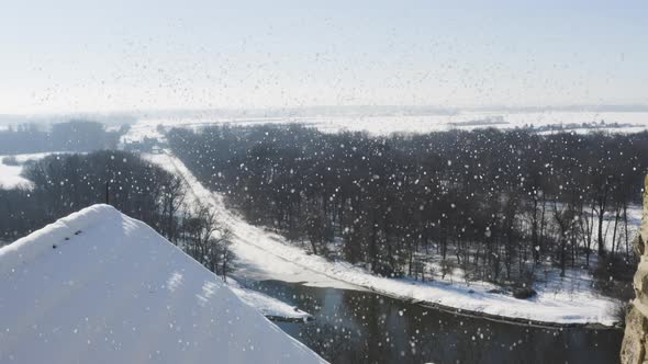 Brick chimney on a roof above a river and forests,falling snow,winter.