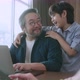 asian male dad using laptop and conversation on smartphone remotely distance working - VideoHive Item for Sale