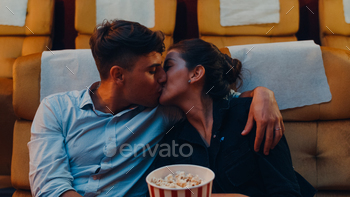 映画館で映画を見ながらロマンチックな瞬間にキスする若い白人カップル。 / Photodune, Misc