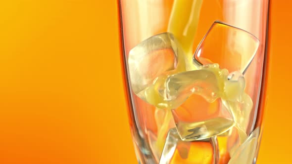 Super Slow Motion Shot of Pouring Fresh Orange Juice Into Glass with Ice Cubes at 1000 Fps