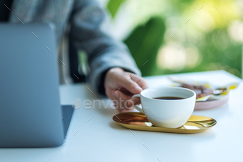 オフィスでコーヒーを飲みながらラップトップコンピューターを使用して作業しているビジネスウーマン / Photodune, Misc