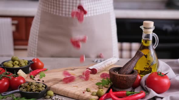 Sliced Fuet Sausage Pieces Falling Onto Wooden Cutting Board at Domestic Kitchen