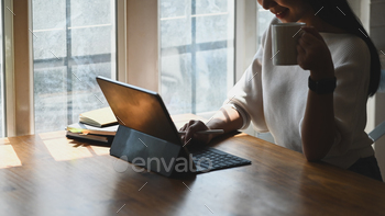 コンピューターのタブレットを使用しながら手にコーヒーカップを保持しているクローズアップの女性。 / Photodune, Misc