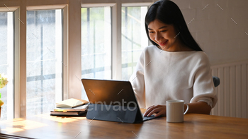 鉢植えの植物の前に座って、コンピューターのタブレットを使用/入力する創造的な女性。 / Photodune, Misc
