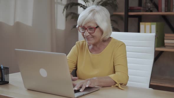 A Senior Concentrated Business Lady Staring at the Screen and Lowered Her Eyeglasses While Using