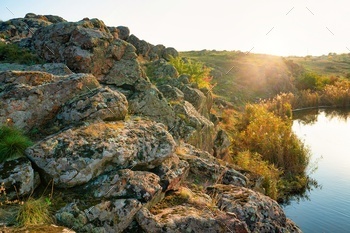 A small pile of stones in a green-yellow field against the background of sky in beautiful Ukraine / Photodune, Misc