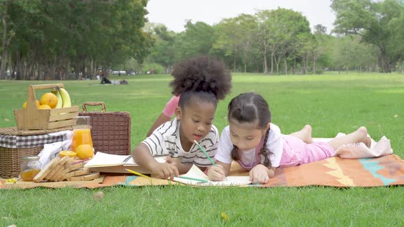 Two African American little girl doing homework on notebook together while sitting on mat 