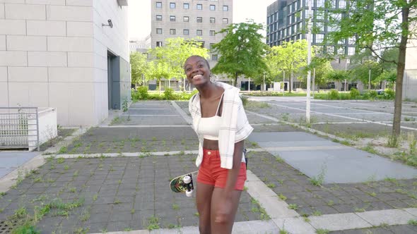 Slow motion shot of young woman with skateboard walking in city