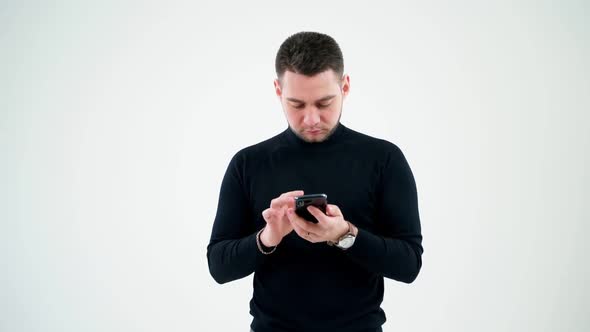Serious man touching the screen of smartphone indoors