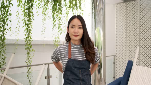 Business owner attractive young Asian  in apron hanging we're open sign