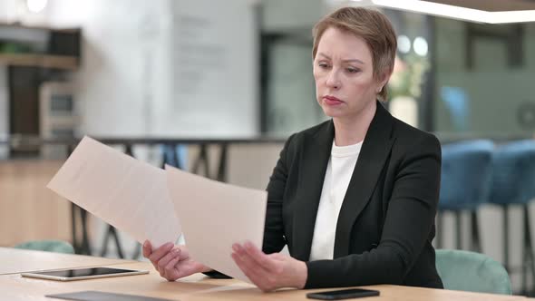 Old Businesswoman Reading Documents in Office 