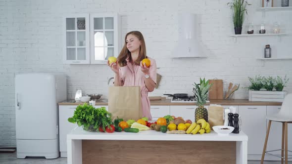 Woman with orange and apple in her hands indoors.