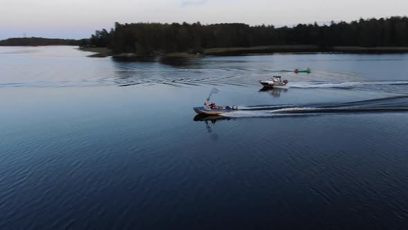 Two Boats Sail Quickly on the Lake in Summer at Sunset