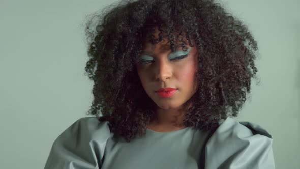 Mixed Race Woman with Big Curly Hair in Leather Fashion Dress in Studio