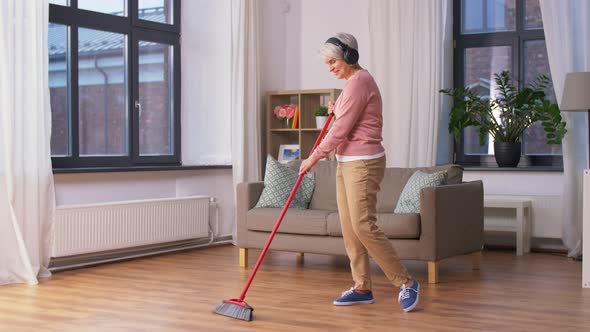 Old Woman in Headphones with Broom Cleaning Floor