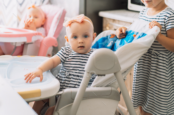 Twins sitting on chairs and older sister / Photodune, Misc