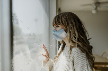 封鎖中に窓の外を見つめているマスクを身に着けている女性 / Photodune, Misc