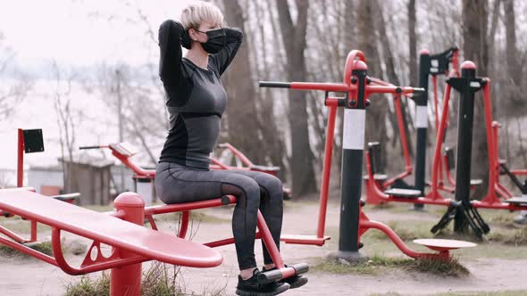The Sporty Woman in a Protective Mask Is Doing Workout in a Park