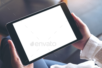 足を組んで座って、空白の白いデスクトップ画面で黒いタブレットPCを保持している女性 / Photodune, Misc