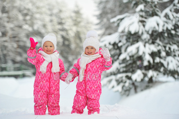 赤いスーツを着た2人の小さな双子の女の子が雪に覆われた冬の森に立っています / Photodune, Misc