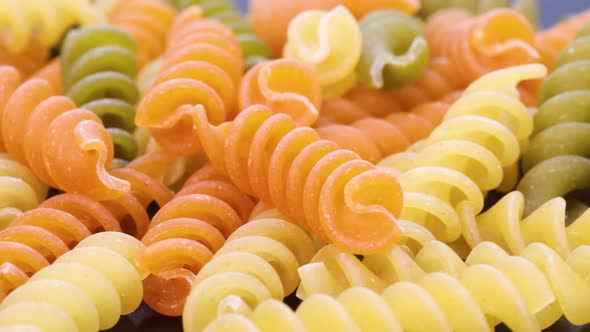 Macro shot of fusilli, italian colored macaroni, macro shot in 4k. Rotating motion, view from above.