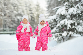 赤いスーツを着た2人の小さな双子の女の子が雪に覆われた冬の森に立っています / Photodune, Misc