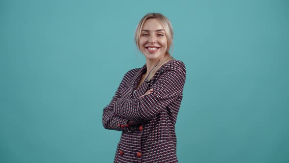 The Portrait of a Confident Blonde Who Happily Puts Her Hands Crossed on Her Chest and Smiles