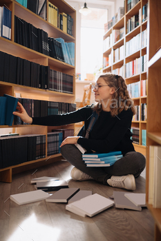 Teenager girl picking a book on a library shelf / Photodune, Misc