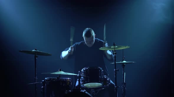 Silhouette Drummer Playing on Drum Kit on Stage in a Dark Studio with Smoke and Neon Lighting